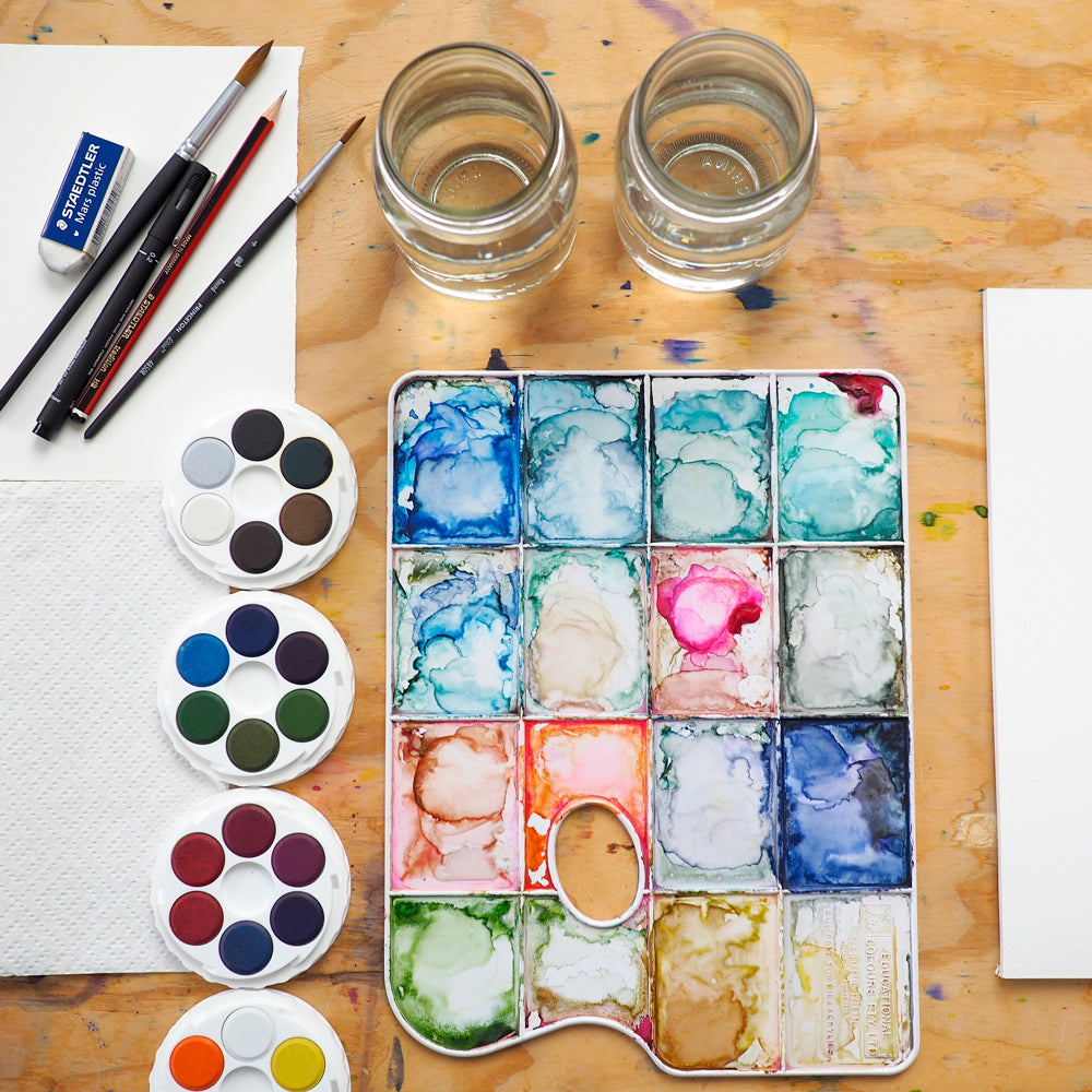 Table set up with paints, brush and paper for Natalie Martin's 1 Day Intro to Watercolour workshop